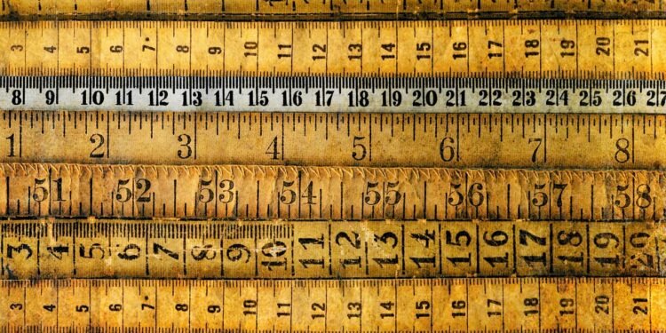 Antique rulers and measuring tapes lie horizontally across the image.