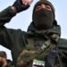 A rebel fighter wearing a balaclava raises his arm