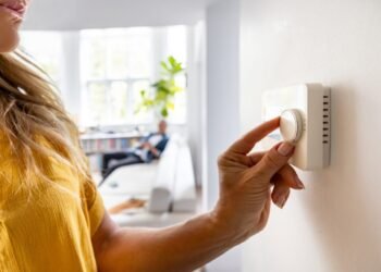 Person turning a thermostat