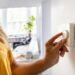 Person turning a thermostat