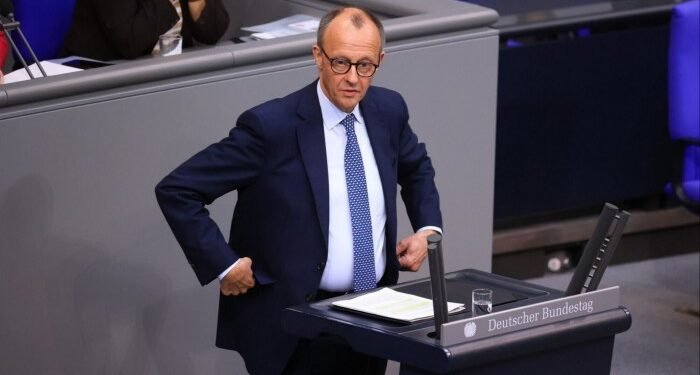 Friedrich Merz stands at a podium at the Bundestag in Berlin