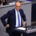 Friedrich Merz stands at a podium at the Bundestag in Berlin