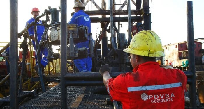 Workers operate flow valves on a PDVSA oil platform