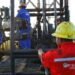 Workers operate flow valves on a PDVSA oil platform