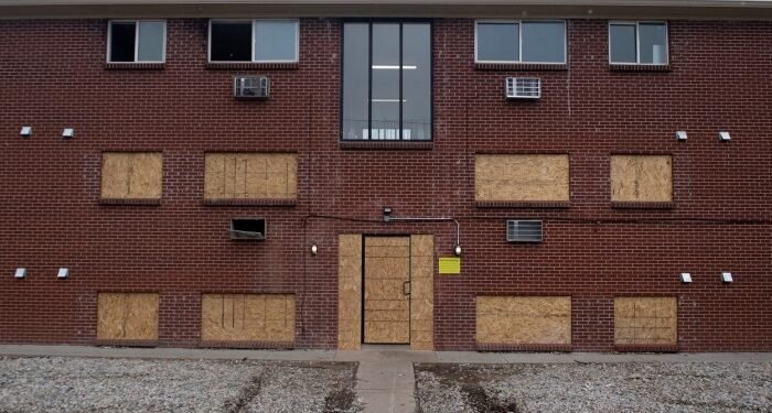 An apartment complex with boarded up windows