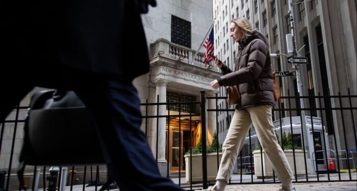 Pedestrians walk past the entrance of the New York Stock Exchange in New York City