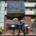 edestrians walk past a broadcast screen of the Bombay Stock Exchange