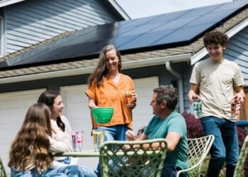 Family at table outdoors near home with solar panels