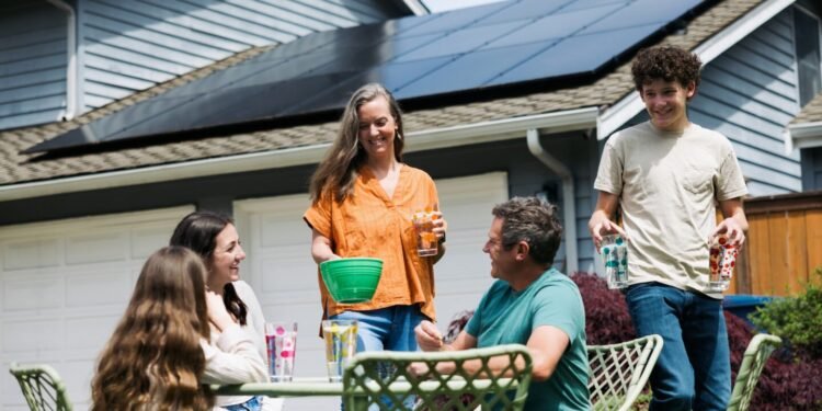 Family at table outdoors near home with solar panels