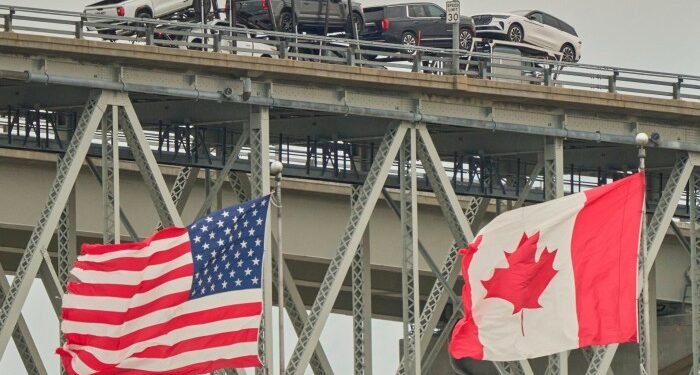 A truck with vehicles crosses the Blue Water Bridge border crossing into the US from Sarnia, Ontario, Canada