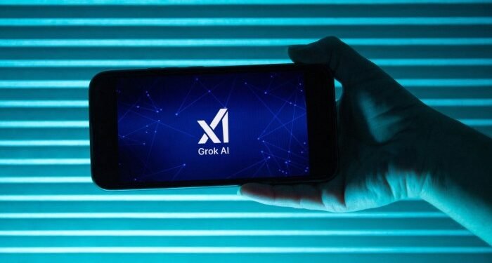 A person holds a telephone displaying the logo of xAI