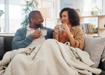 older adult couple sharing coffee on sofa