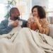 older adult couple sharing coffee on sofa