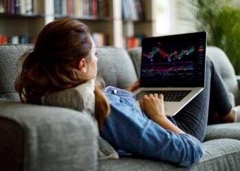 Person on couch looking at stock chart on laptop