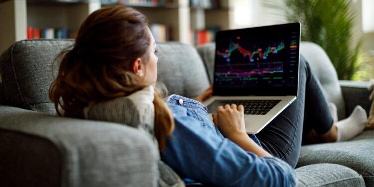 Person on couch looking at stock chart on laptop