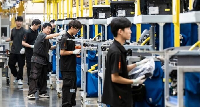 Employees work along an assembly line in China, assembling automotive components.