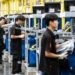 Employees work along an assembly line in China, assembling automotive components.