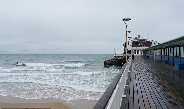 Surfers won't be the only ones taking advantage of stormy weather this weekend, some households will pay nothing for electricity. A person surfs in the sea off of Bournemouth Pier