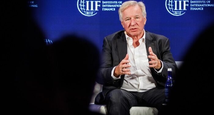 Martin Gilbert speaks on stage, gesturing with his hands, during the IIF annual membership meeting.