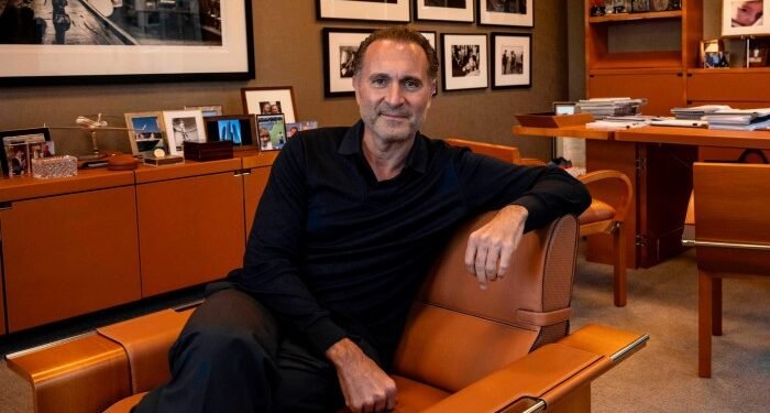 Gerry Cardinale sits in a brown leather chair in an office decorated with framed photos and shelves of memorabilia.