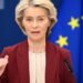 Ursula Von der Leyen speaks at a podium with an EU flag in the background during a NATO press conference.