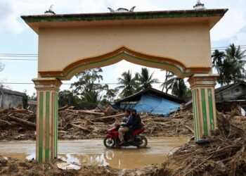 Indonesians climb over logs in walk to aid centre as flood deaths exceed 900