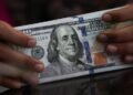 Dollar holds gains in thin trading as markets await Fed minutes, US GDP