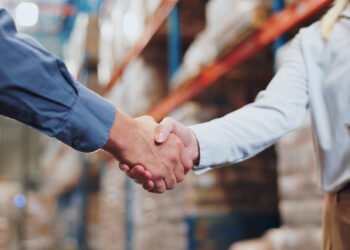 Handshake, agreement and teamwork for people in warehouse, meeting and deal for supply chain. Partnership, logistics and management shaking hands, distribution collaboration and courier company