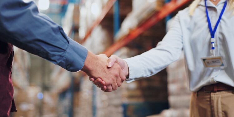 Handshake, agreement and teamwork for people in warehouse, meeting and deal for supply chain. Partnership, logistics and management shaking hands, distribution collaboration and courier company